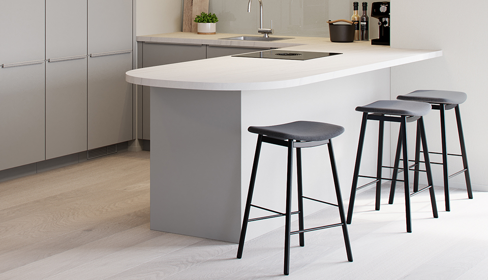 Cuisine moderne avec îlot central gris clair, plan de travail blanc, trois tabourets noirs, et évier en acier inoxydable, sur fond de sol en bois clair.
