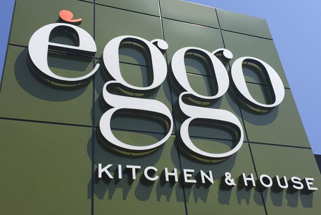 Panneau vert avec le logo blanc "èggo" et texte "KITCHEN & HOUSE" en façade d'un bâtiment.