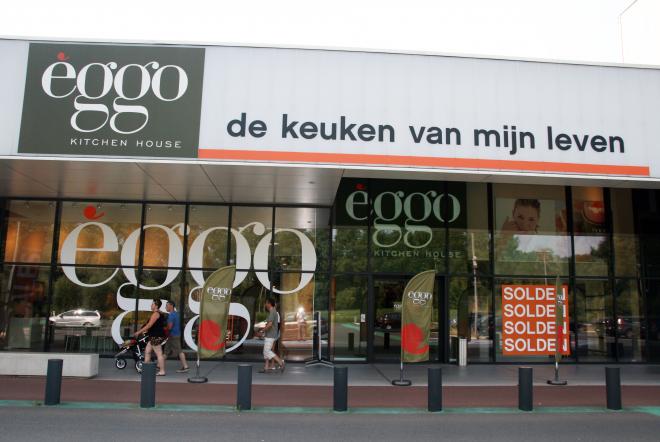 Façade d'un magasin èggo avec de grandes vitrines, affiches de soldes rouges, et logo vert sur fond blanc.
