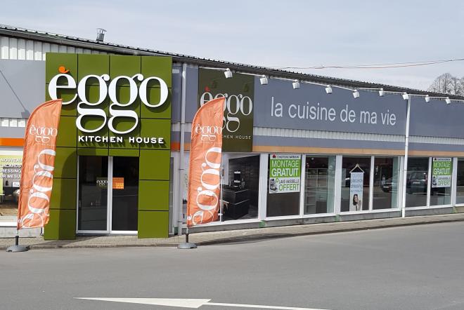 Façade du magasin èggo avec enseigne verte et orange, deux drapeaux orange, et vitrines affichant des offres de montage gratuit.