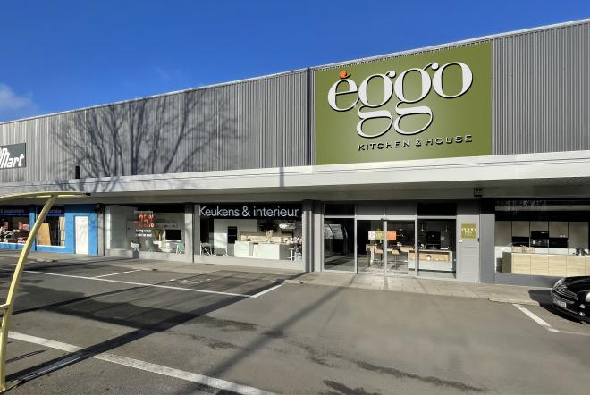 Façade d'un magasin èggo avec un panneau vert et des vitrines affichant des cuisines, sur un parking ensoleillé.