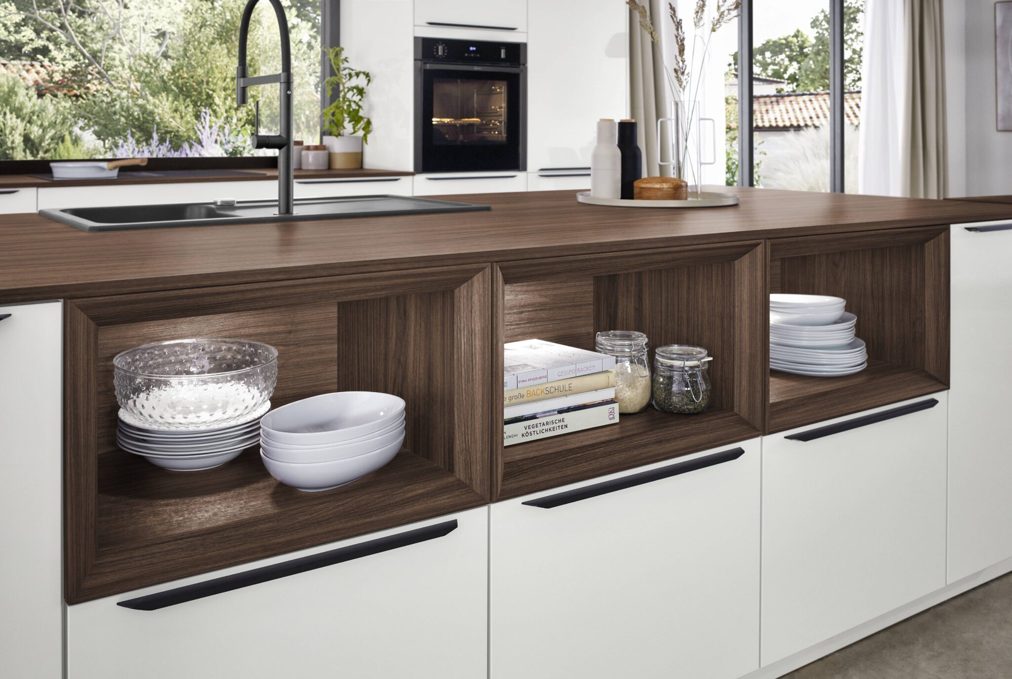 MEUBLE_30876_23_Novalux_512_R1_D Des étagères en bois foncé avec vaisselle blanche, livres et bocaux en verre, intégrées dans une cuisine moderne avec plan de travail en bois.