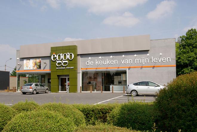 Façade d'un magasin èggo avec deux voitures garées devant, et une enseigne verte avec le logo èggo sur la gauche.