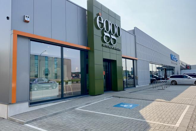 Façade d'un magasin èggo avec une enseigne verte et des vitrines, situé dans un centre commercial avec un parking à l'avant.