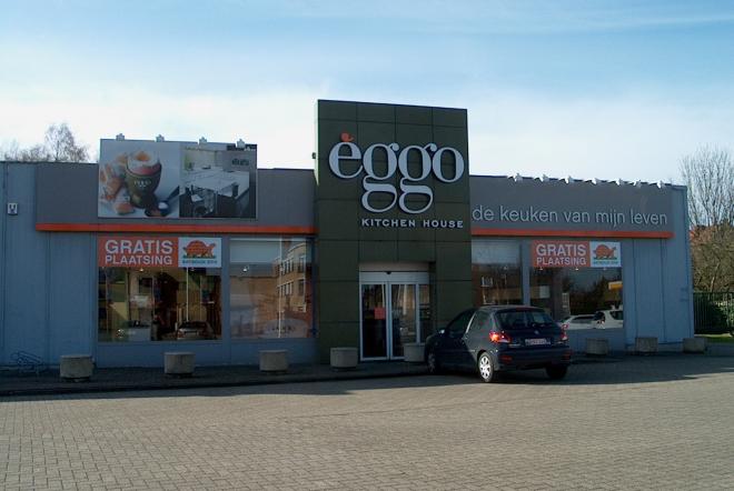 Façade du magasin èggo avec enseigne centrale, voiture stationnée devant, et affiches promotionnelles sur les vitrines.