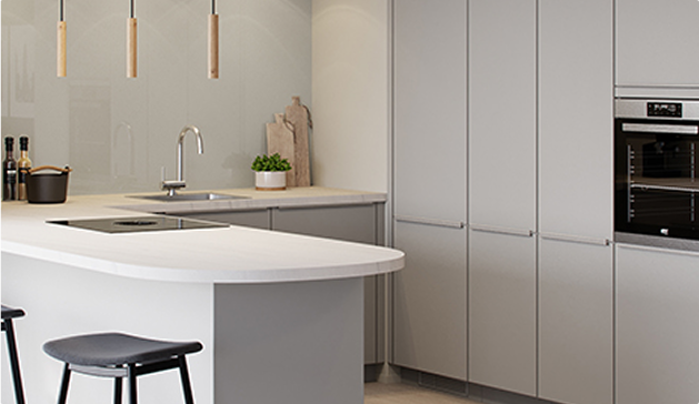 Cuisine moderne avec îlot central blanc, armoires grises, tabourets noirs, et luminaires suspendus en bois. Un four encastré visible à droite.